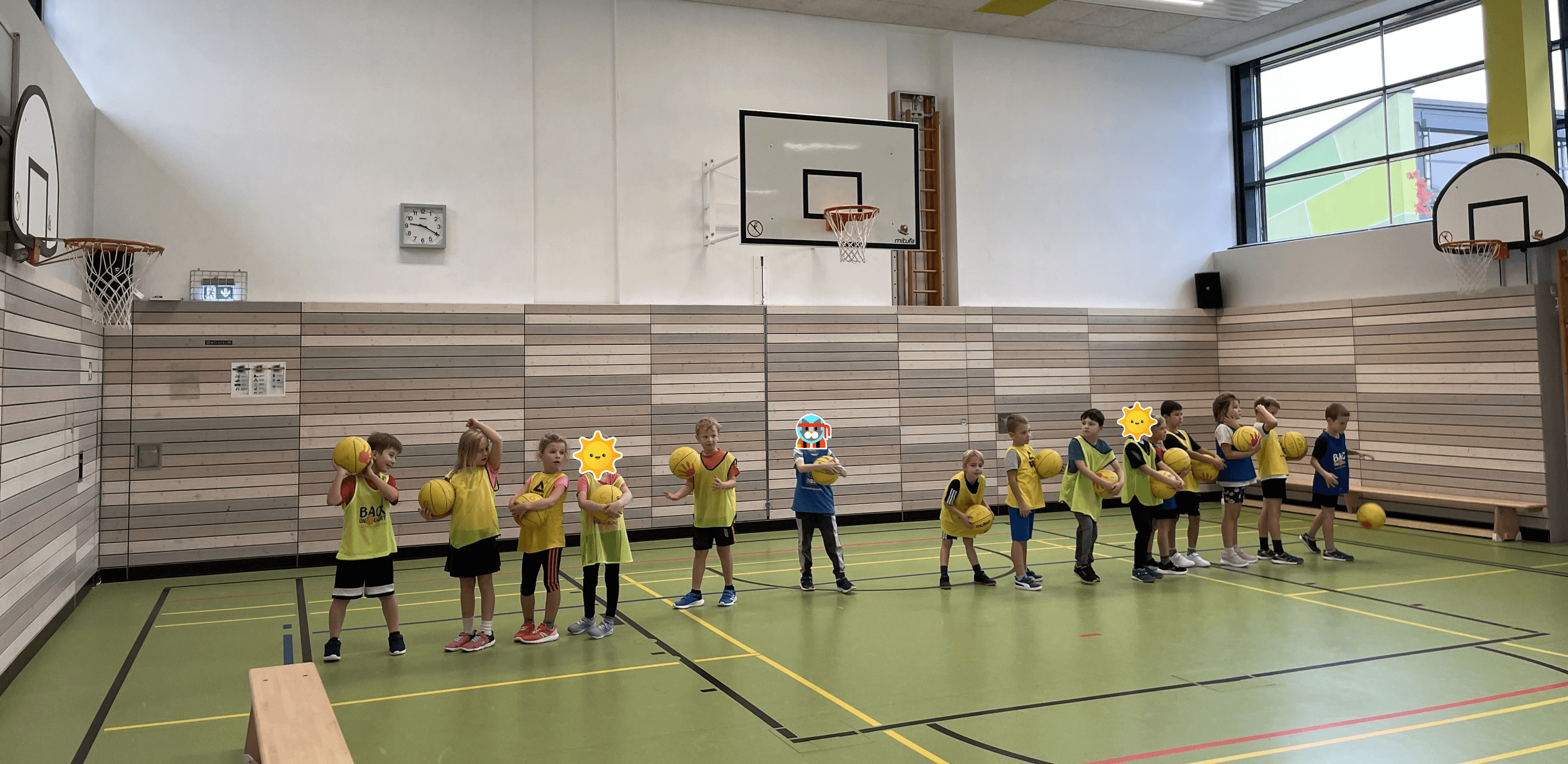 Kinder in einer Reihe mit gelben Basketbällen