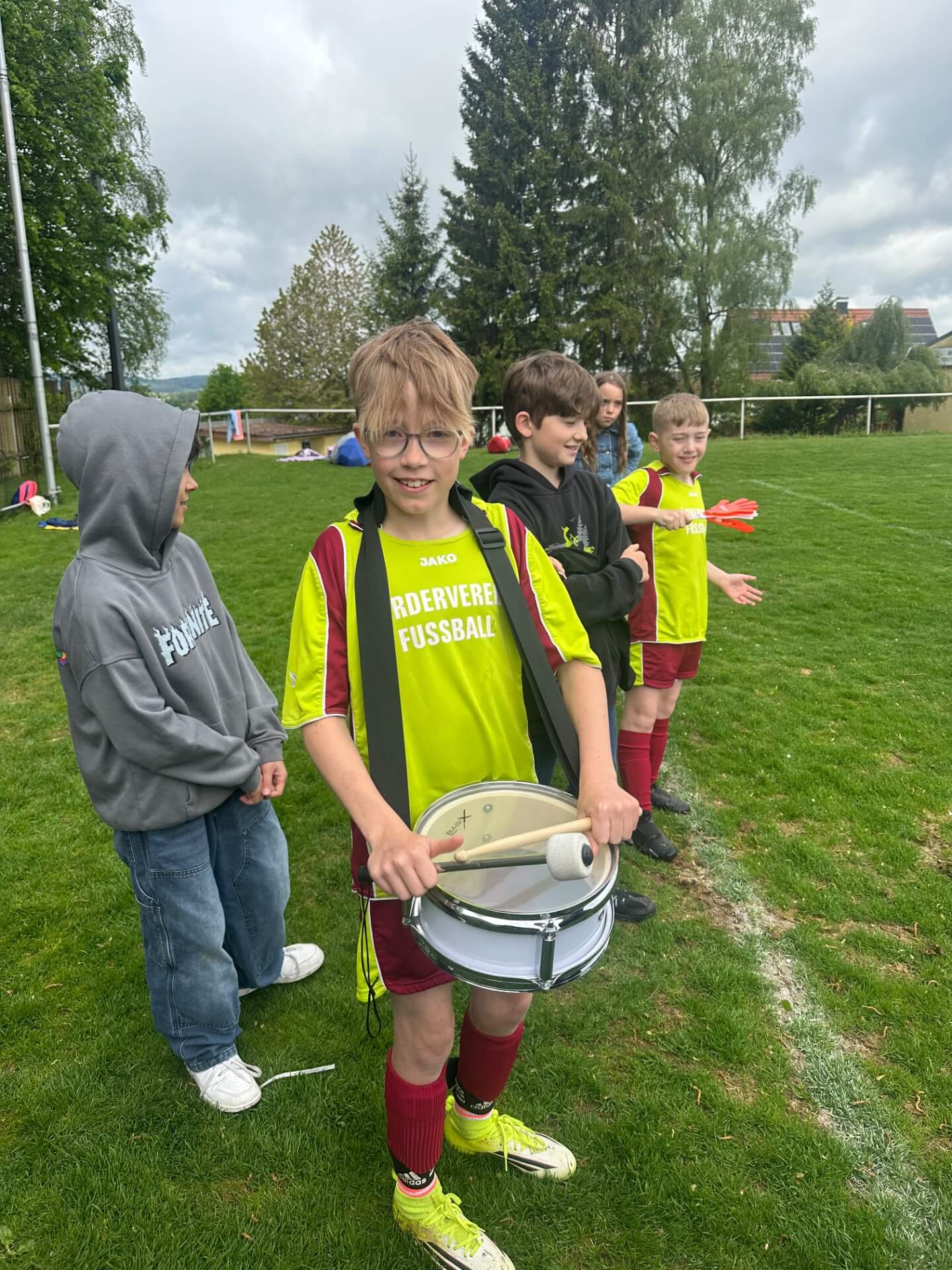 Junge mit Trommel feuert beim Fußballspiel seine Klasse an