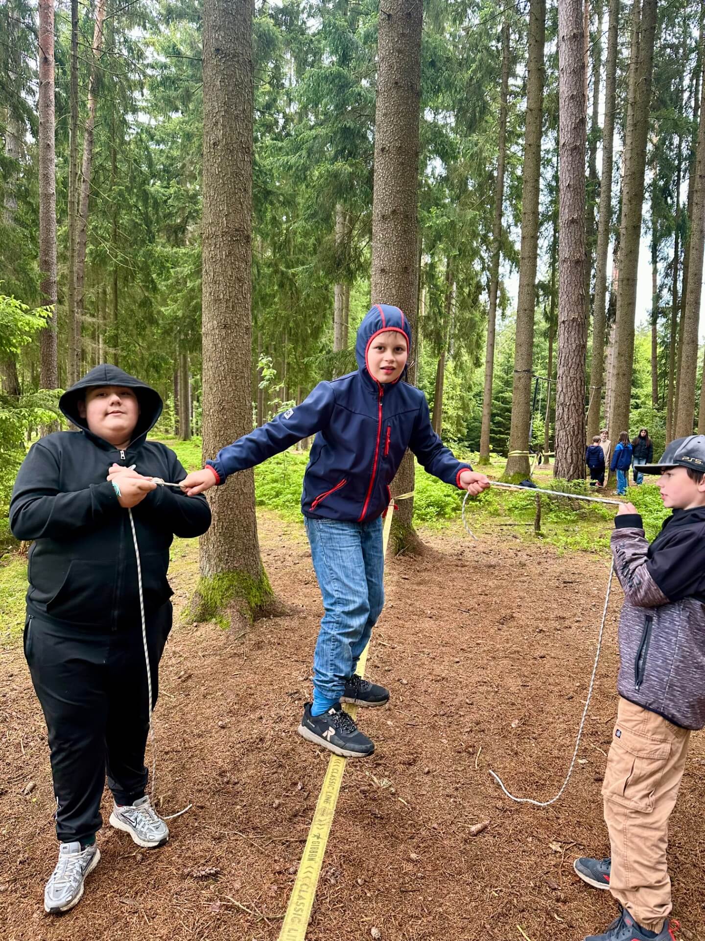 Junge auf einer Slag-Line im Wald seine Freunde helfen ihm