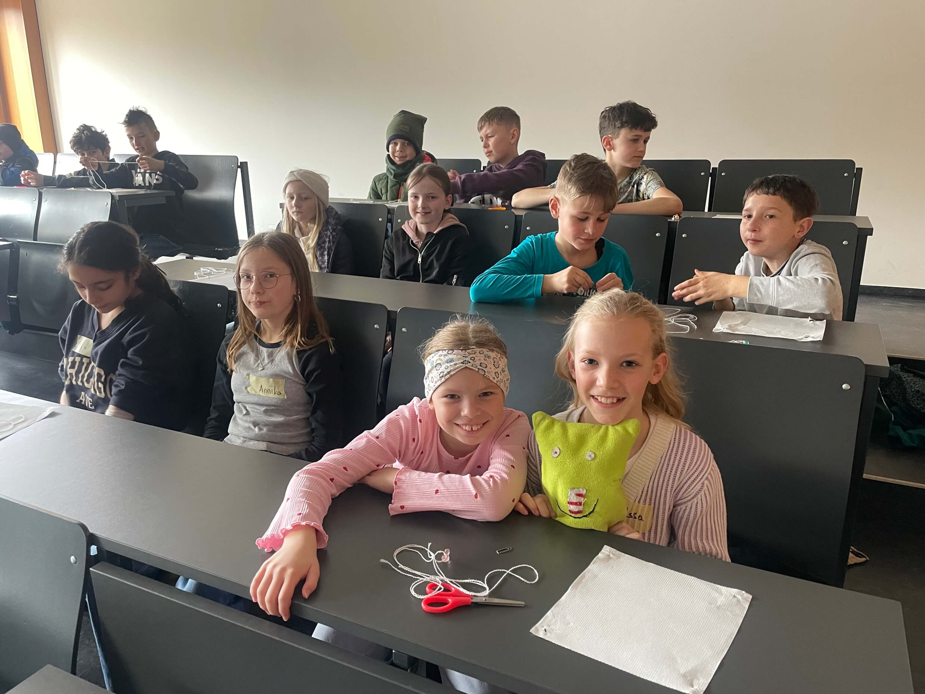 Klasse sitzt in einem Biologiesaal und baut Fallschirme aus Faden und Papier