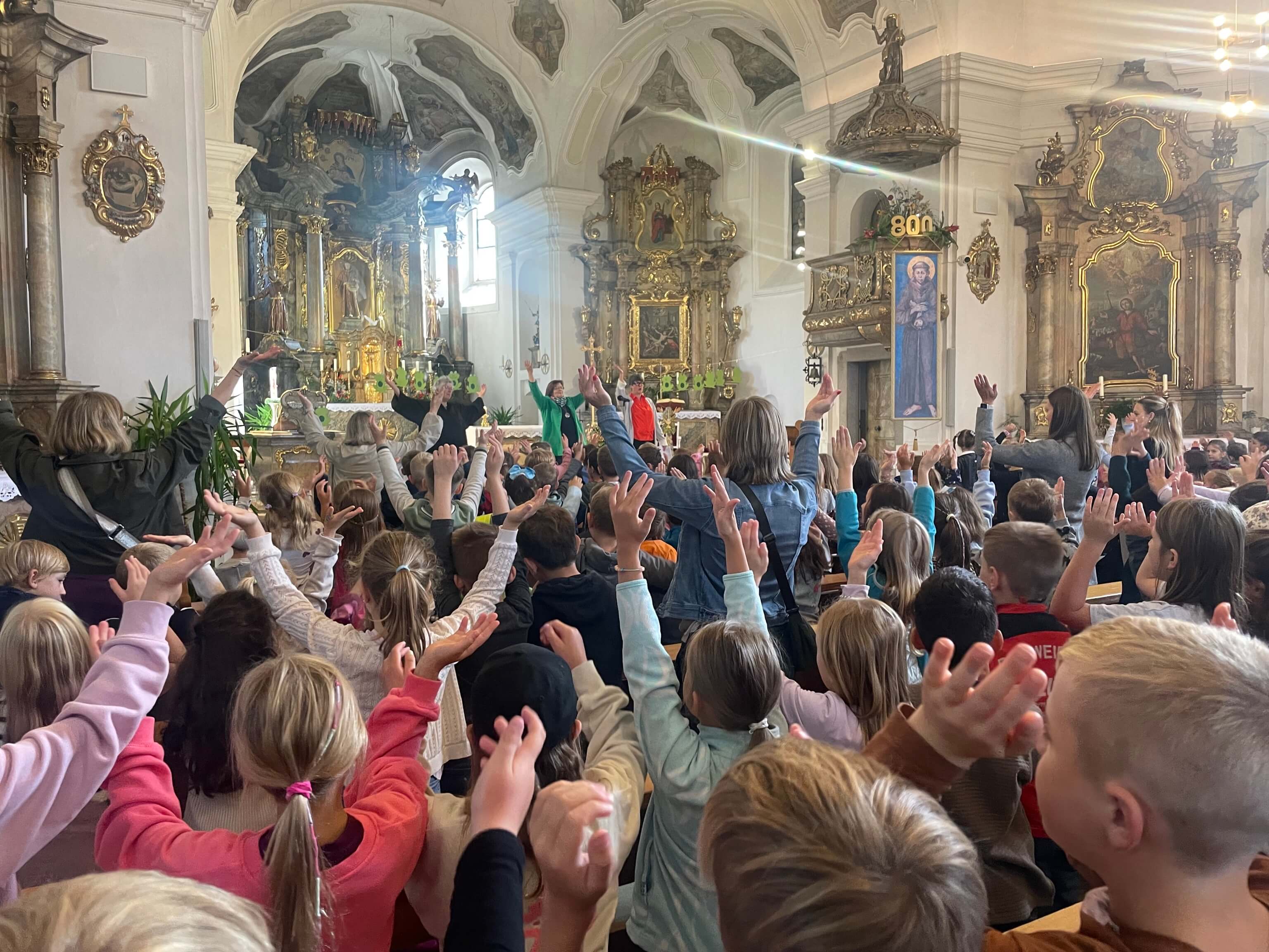 Kinder singen mit erhobenen Händen ein Lied in der Kirche